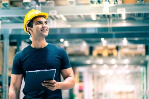 smart-indian-engineer-man-wearing-safety-helmet-doing-stock-tick-check-cardboard-stock-product-management-factory-warehouse-background